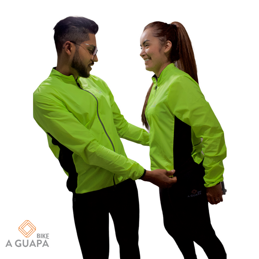Hombre y mujer vistiendo la chaqueta cortavientos ligera y de alta visibilidad para ciclismo en color verde neón de A Guapa Bike.