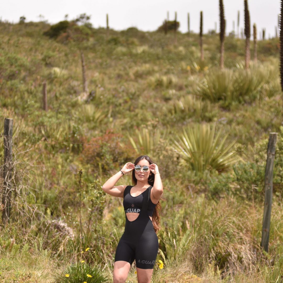 Modelo ajustándose las gafas en ruta con licra de ciclismo negra Pro Max para mujer