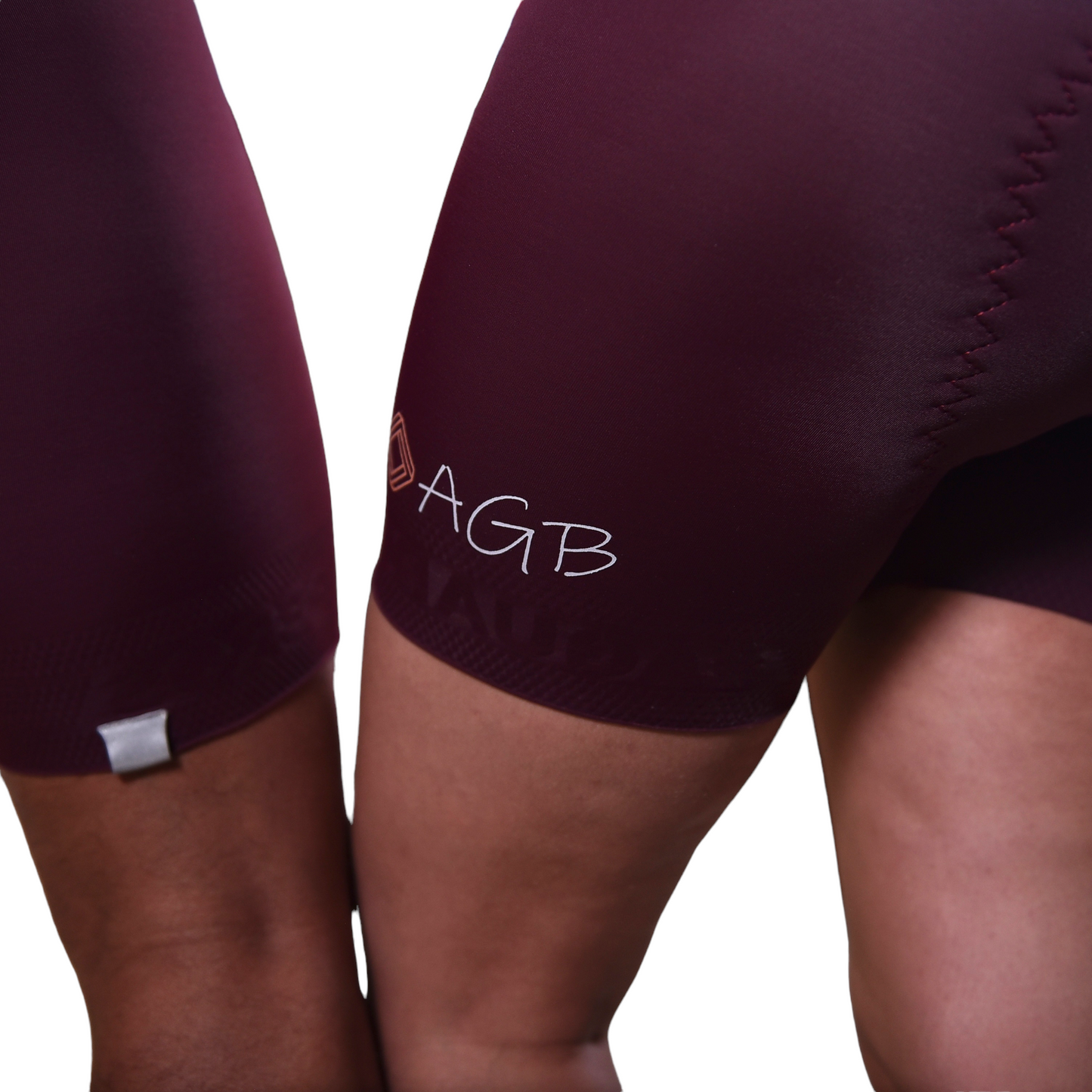 Primer plano del logo reflectivo AGB en la pierna de la licra vino tinto para mujer