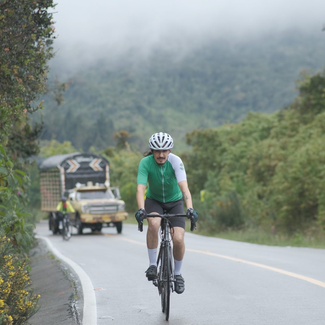 Modelo mostrando el jersey de ciclismo a guapa bike color verde eco en carretera sobre vicicleta.