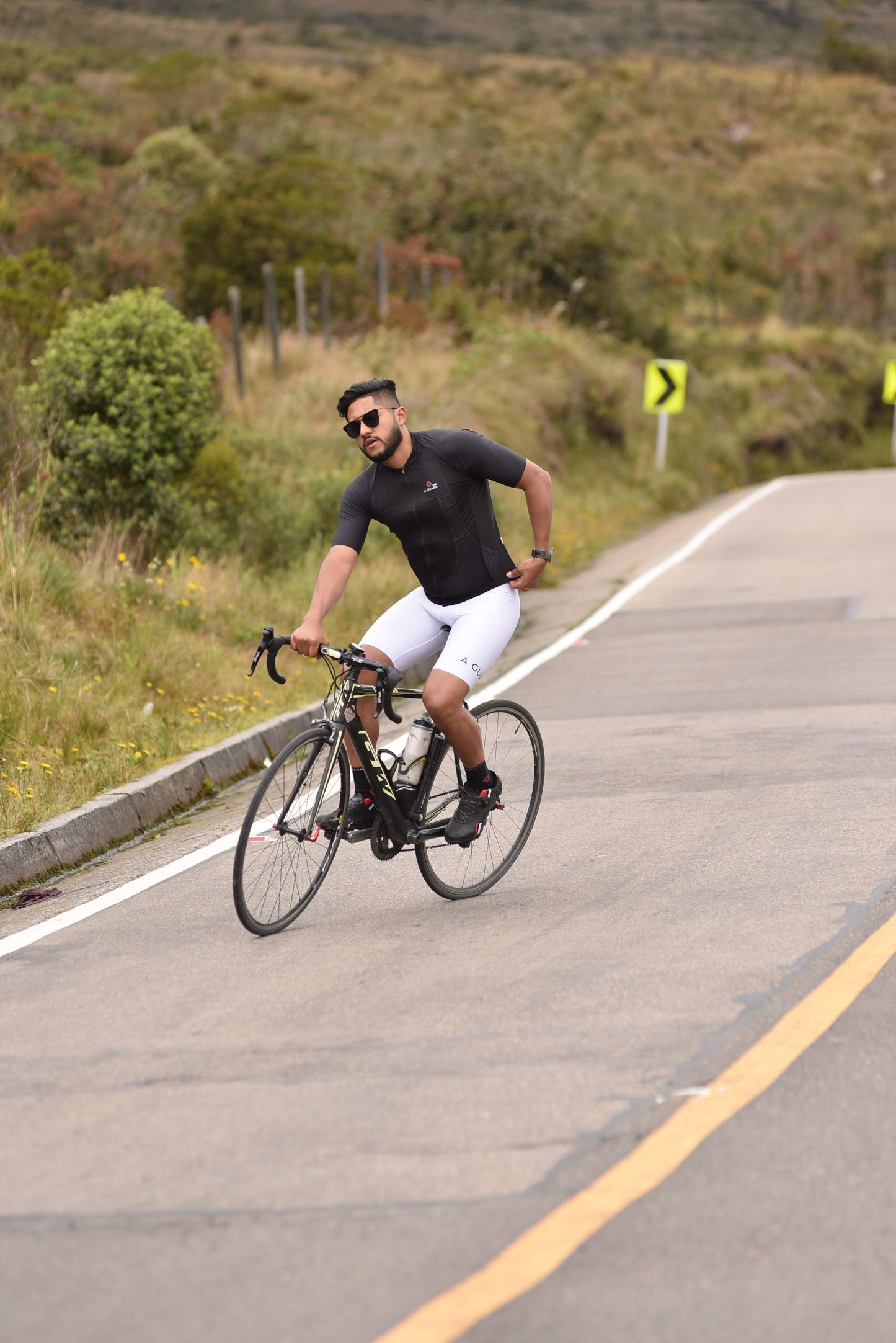 Ciclista en ruta de montaña usando licra de ciclismo para hombre blanca en su bicicleta